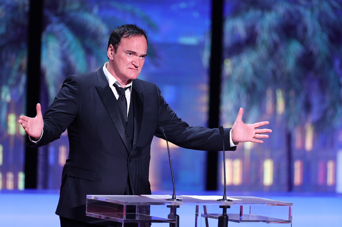 Quentin Tarantino posing in a suit on stage at the 76th annual Cannes film festival.