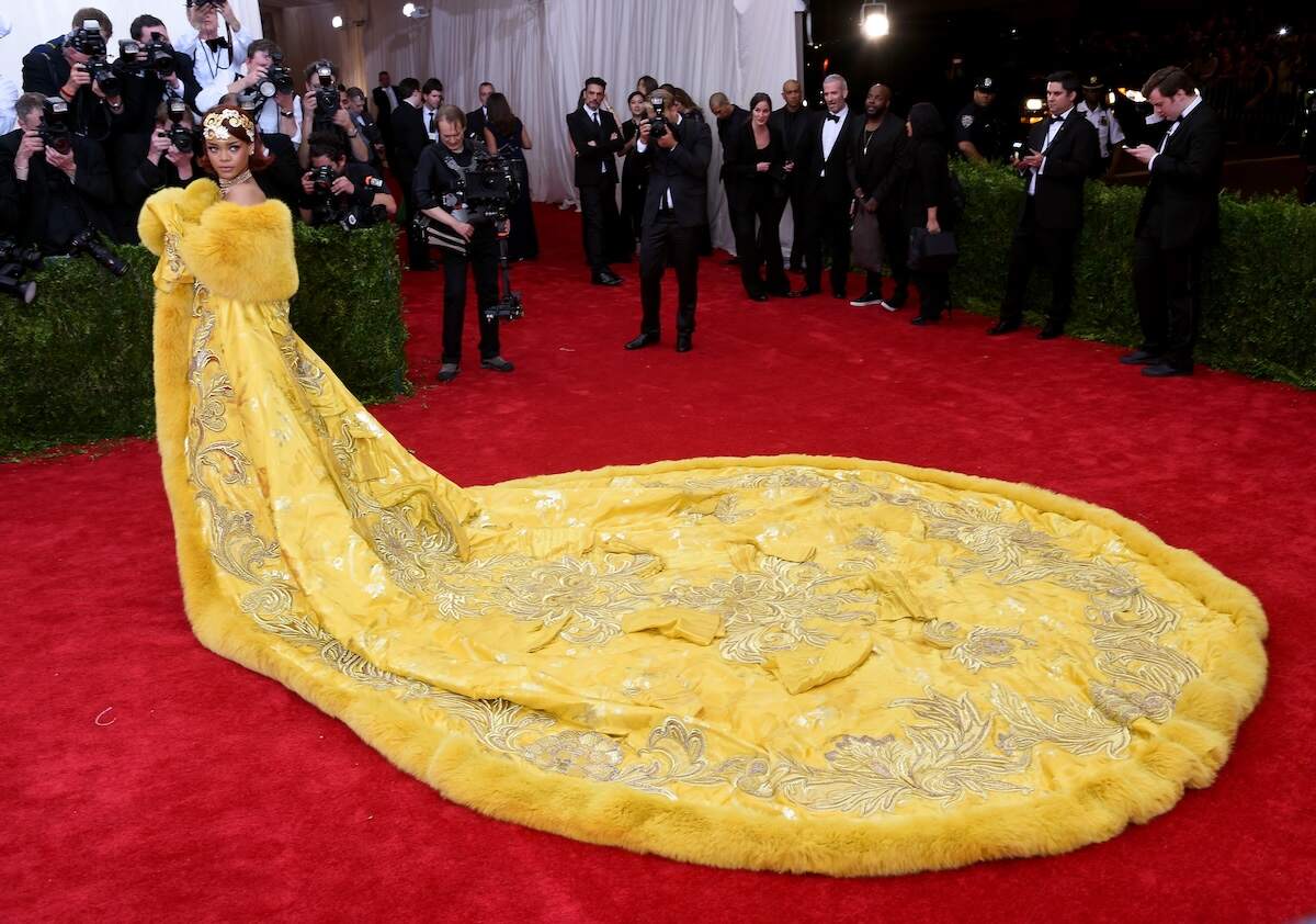 Singer Rihanna wears a long yellow gown trimmed in fur at the 2015 Meta Gala