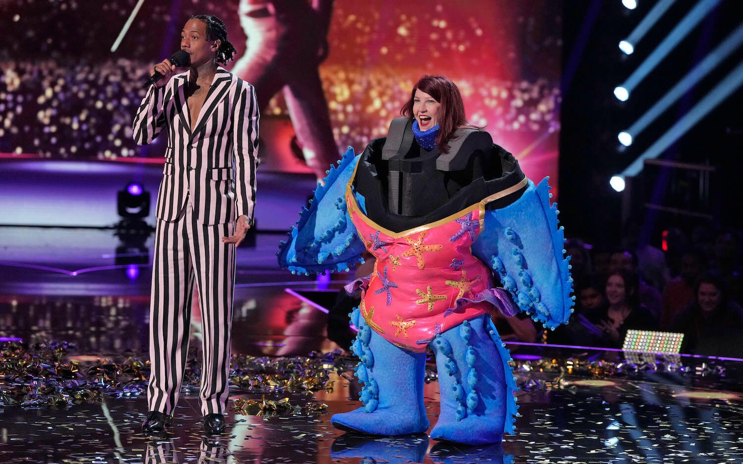 Nick Cannon standing next to Kate Flannery dressed as Starfish on stage in 'The Masked Singer' Season 11