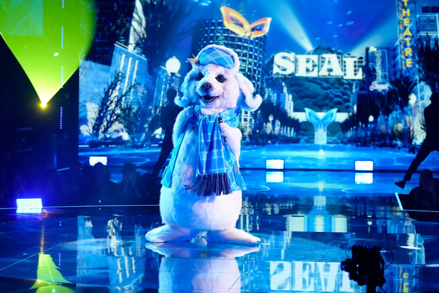 A man singing in a seal costume on stage bathed in blue light on 'The Masked Singer' Season 11