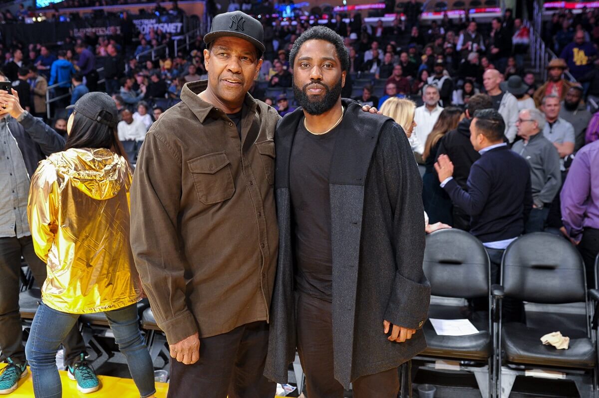 John David Washington posing next to his dad Denzel Washington on a basketball court.