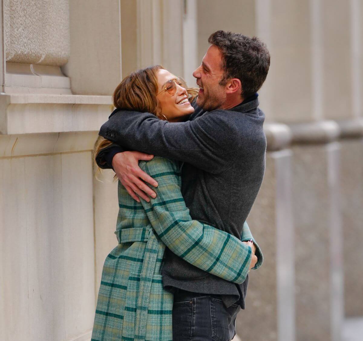 Jennifer Lopez wears a green coat and embraces Ben Affleck. He wears a gray coat.