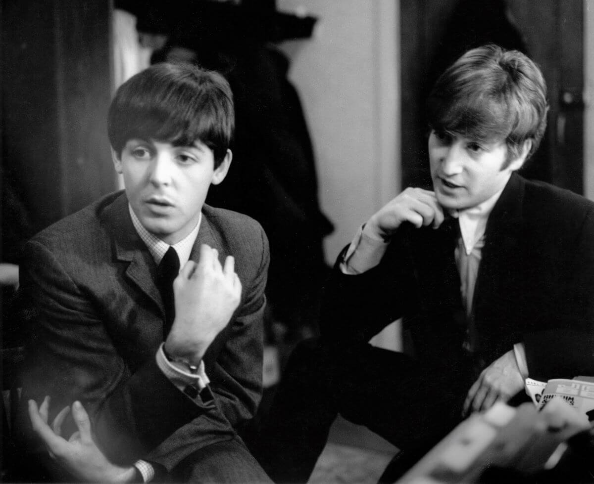 A black and white picture of Paul McCartney and John Lennon sitting next to each other.