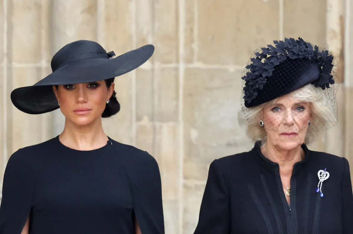 Meghan Markle and Queen Camilla stand near each other wearing black.