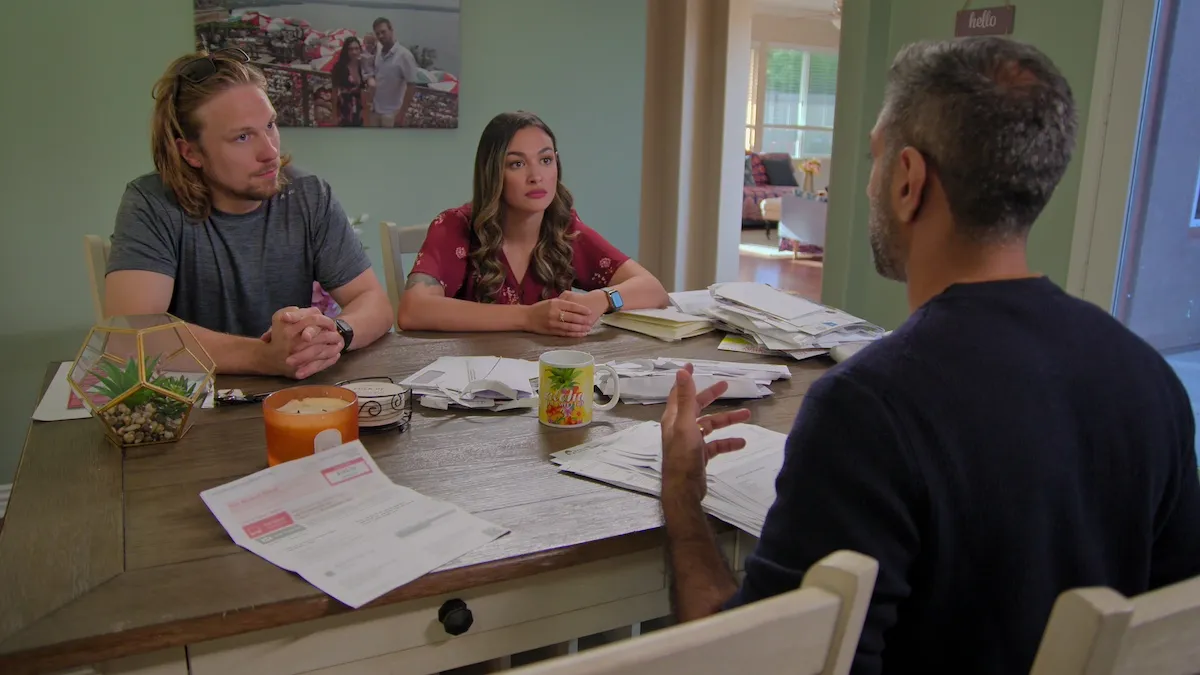 Matt and Amani of '90 Day Fiance' sitting at a table surrounding by paperwork in Netflix's 'How to Get Rich'