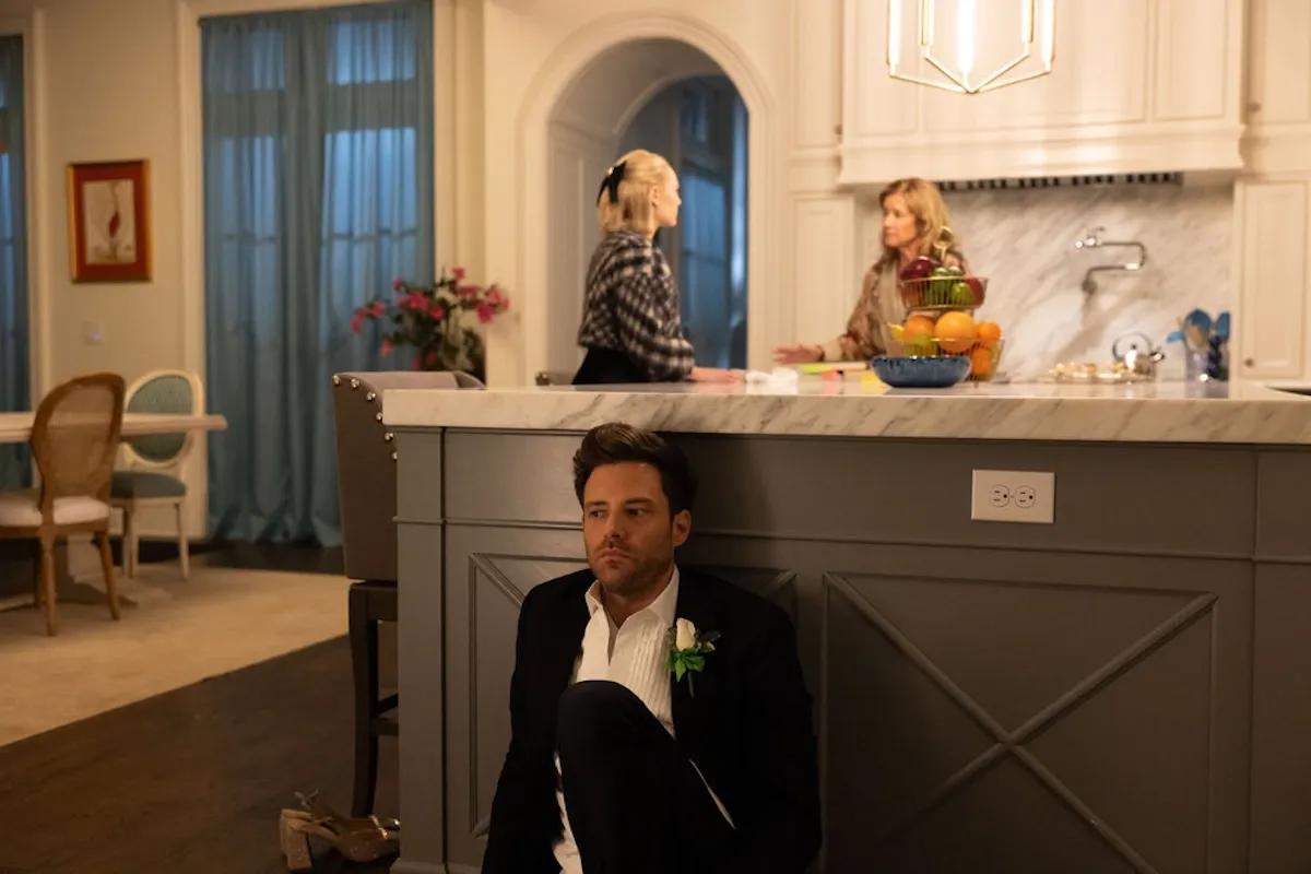 Brett hiding behind a kitchen and island with Patty and Alice behind him in 'Grosse Pointe Garden Society'