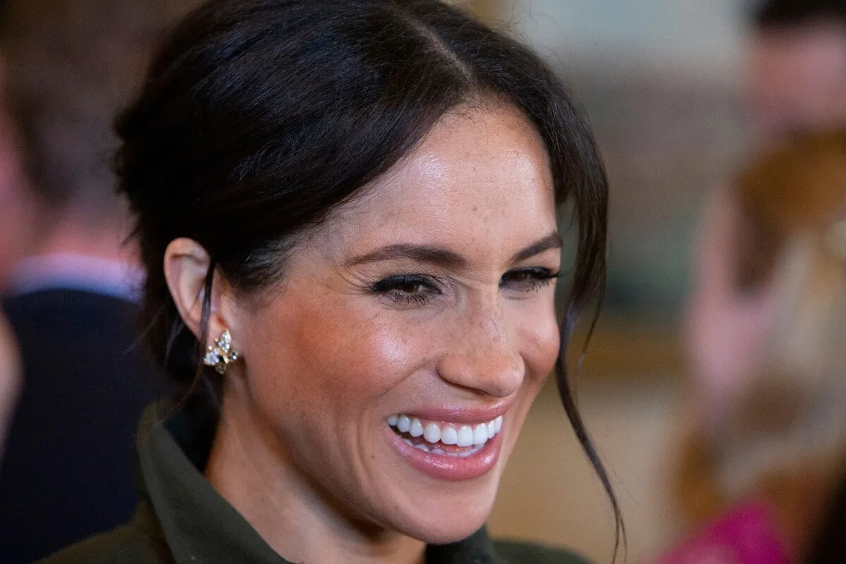 Meghan Markle smiles during a reception hosted by the Governor General at Admiralty House in Sydney while wearing a pair of butterfly earrings