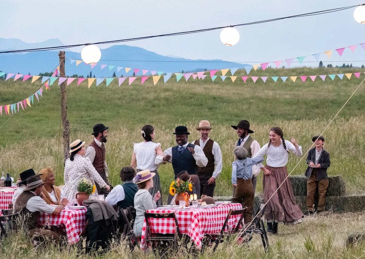 Families gather around tables with checked tablecloths in 'Back to the Frontier'