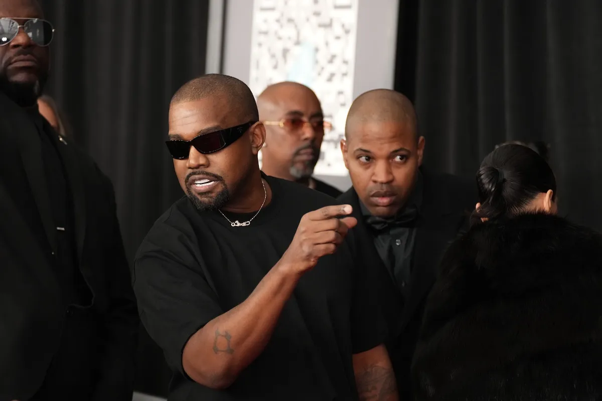 Kanye West in a black T-shirt pointing at something
