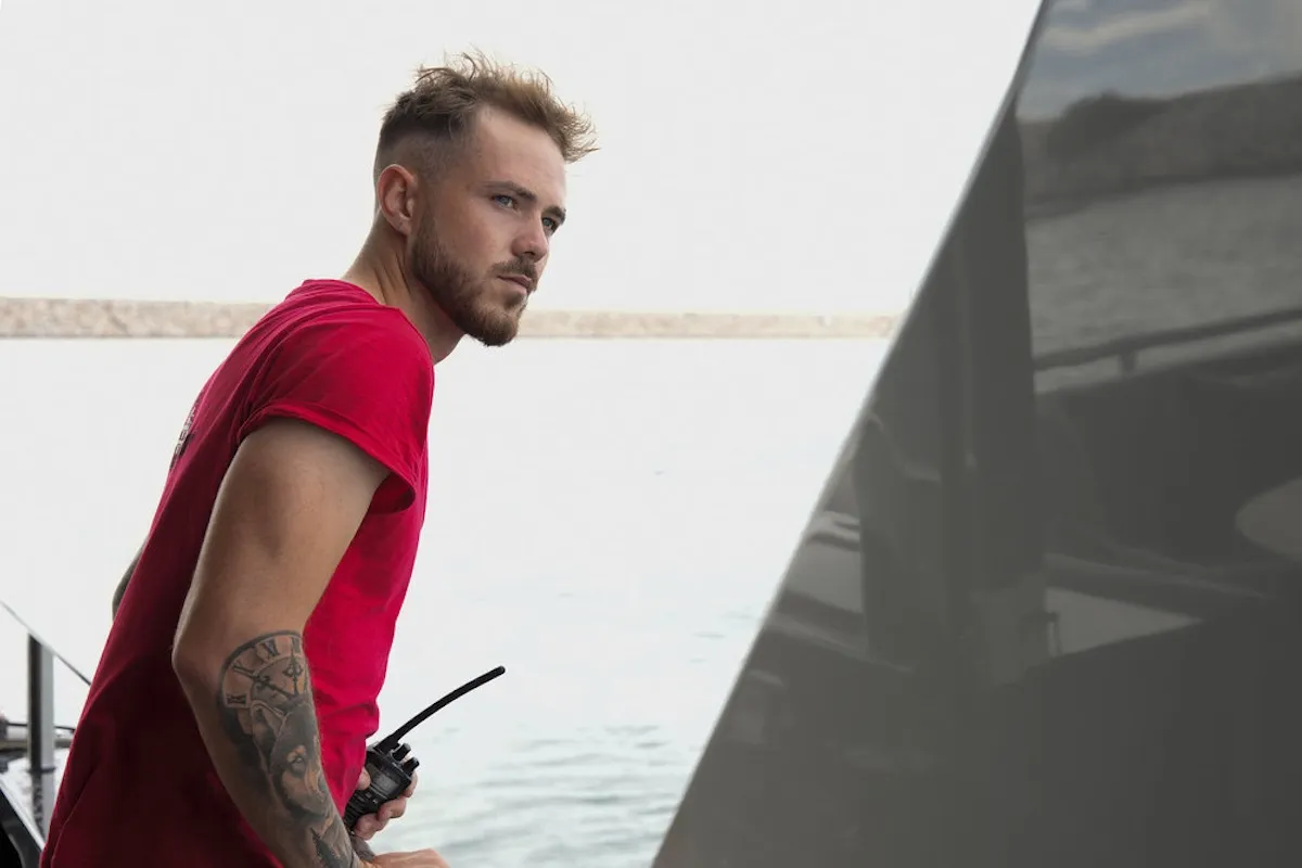 Man in red t-shirt looking over edge of a ship