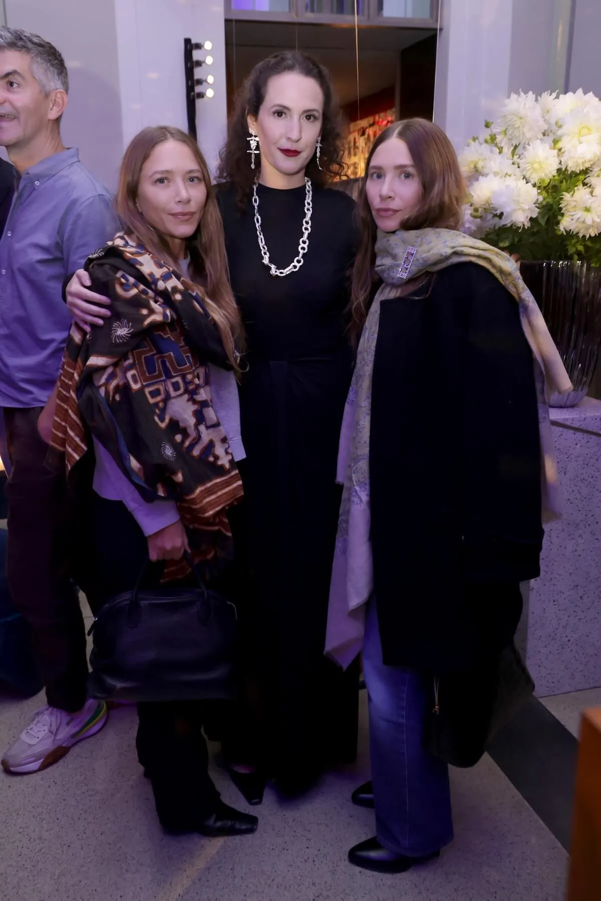 Mary-Kate and Ashley Olsen standing on either side of a woman with dark hair