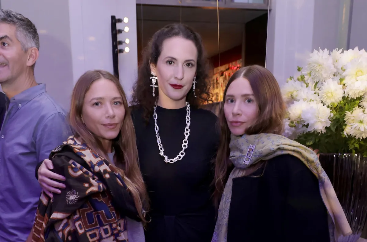 Mary-Kate and Ashley Olsen standing on either side of a woman with dark hair