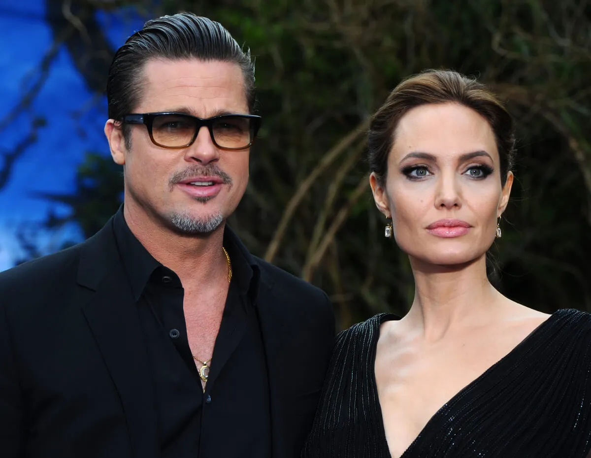 Angelina Jolie and Brad Pitt wear black and stand together. He wears sunglasses.