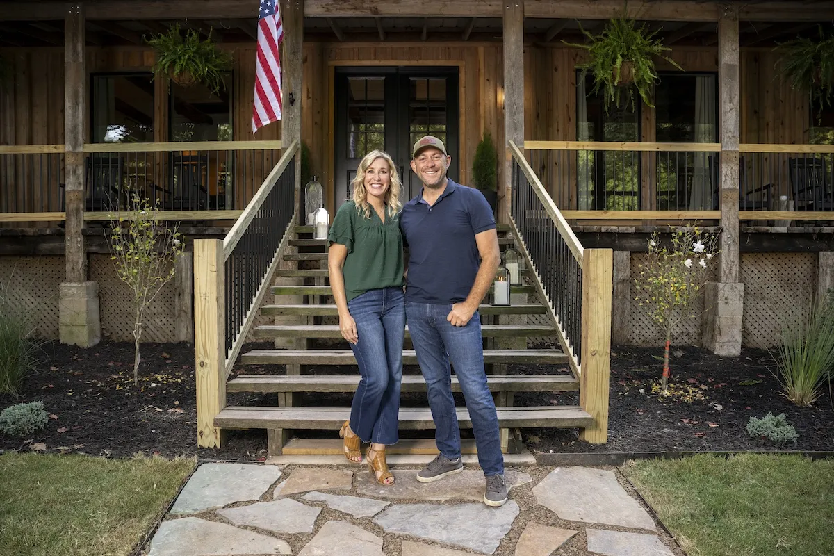Jenny and Dave Marrs of HGTV's 'Fixer to Fabulous' pose for a photo in front of a front porch with an American flag