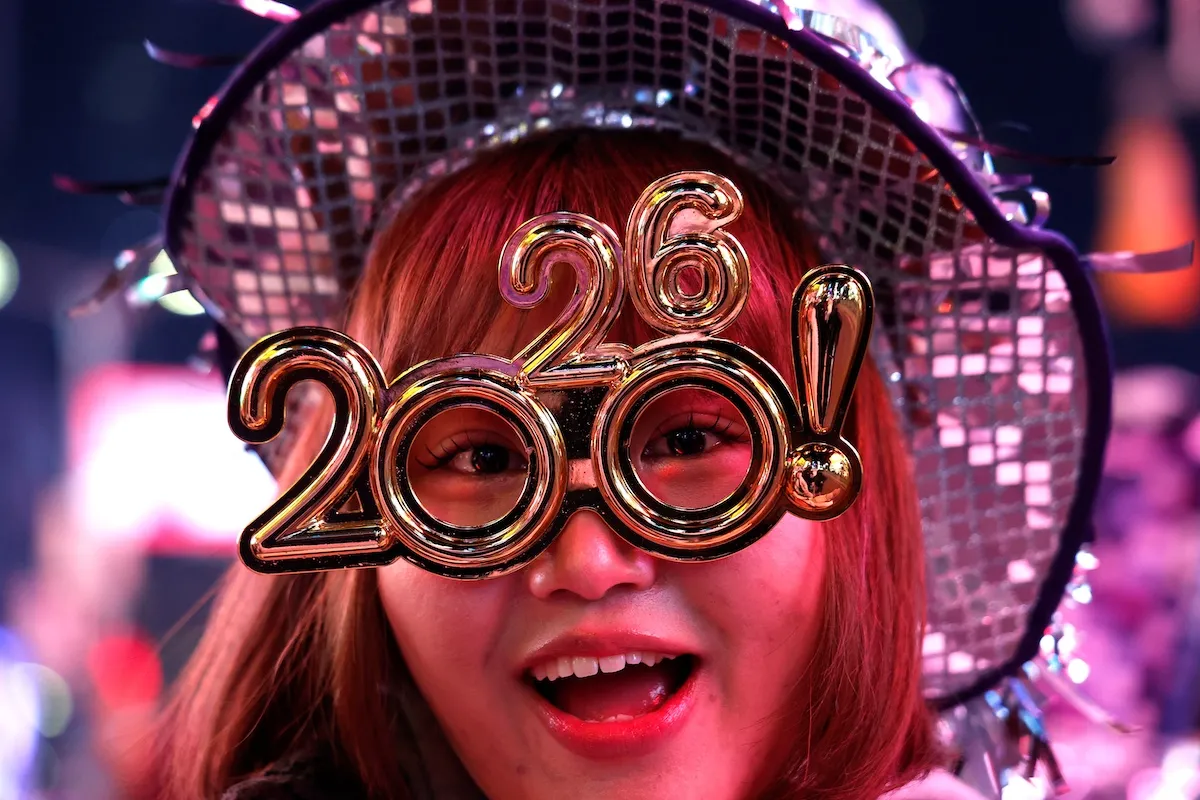 Woman wearing novelty 2026 glasses in Times Square on New Year's Eve