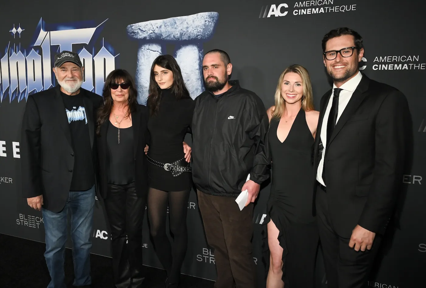 Rob Reiner, Michele Singer, Romy Reiner, Nick Reiner, Maria Gilfillan, and Jake Reiner posing together at a movie premiere against a dark background