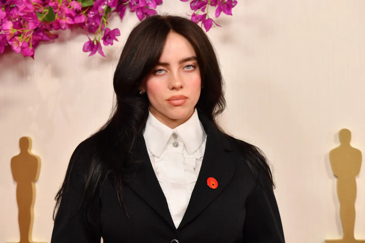 Billie Eilish wears a white shirt and black jacket.