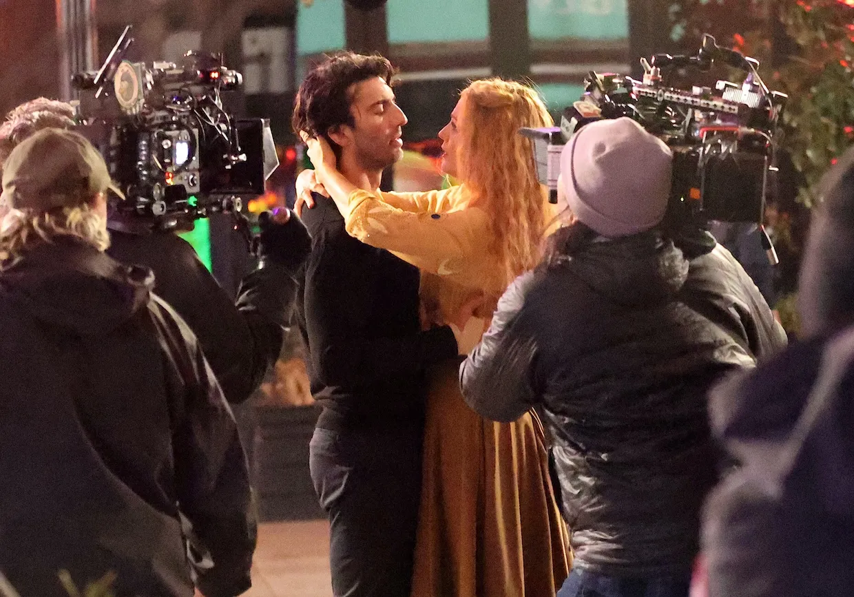 Blake Lively with her arms around Justin Baldoni's neck as she's looking into his eyes on the set of 'It Ends with Us.' They're surrounded by cameras.