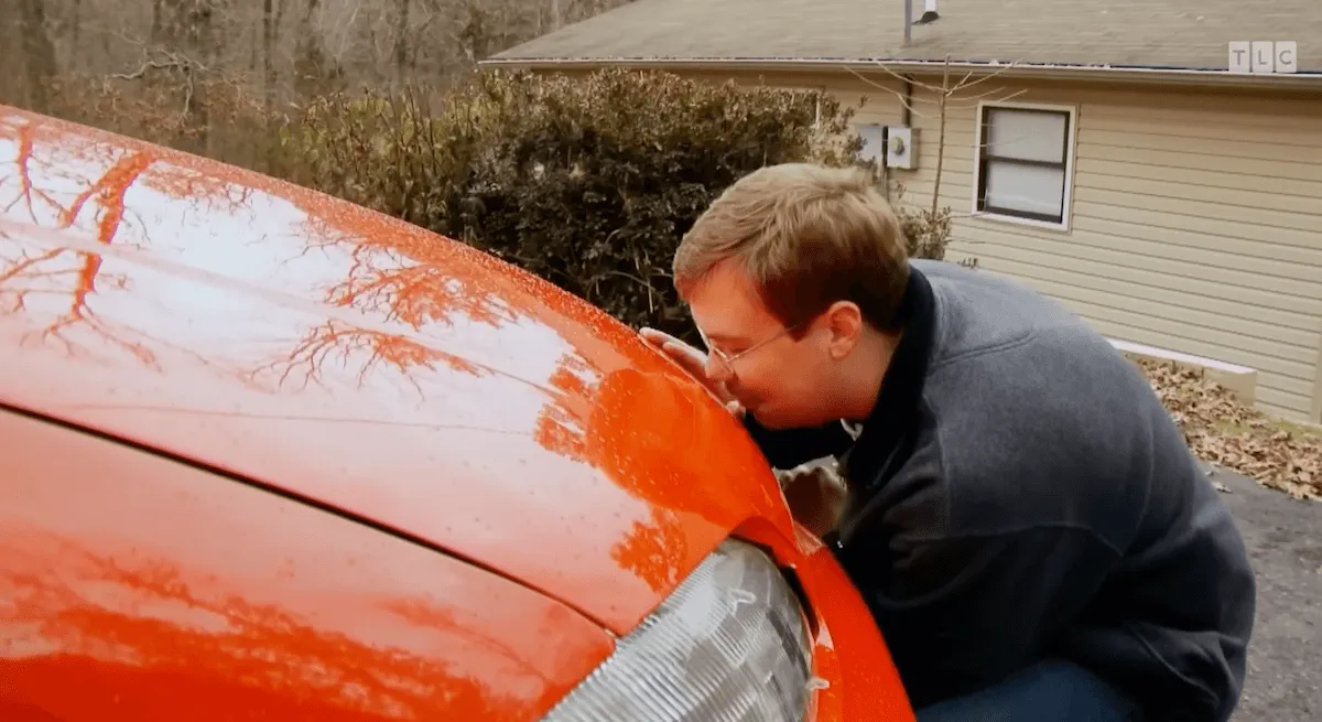 Man kissing the hood of a red car on 'My Strange Addiction'