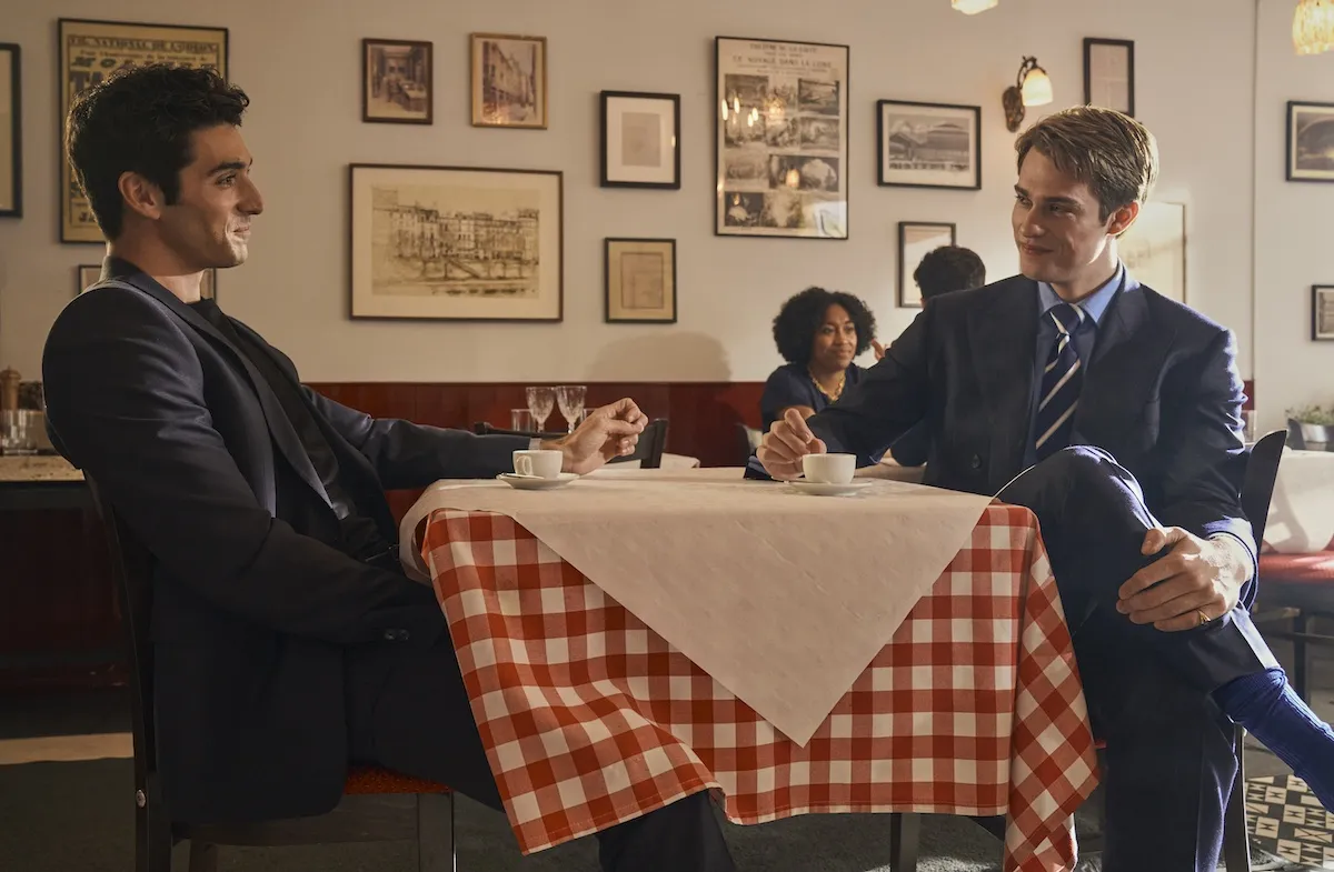 Alex and Henry sitting across from each other at a table in 'Red, White & Royal Blue'