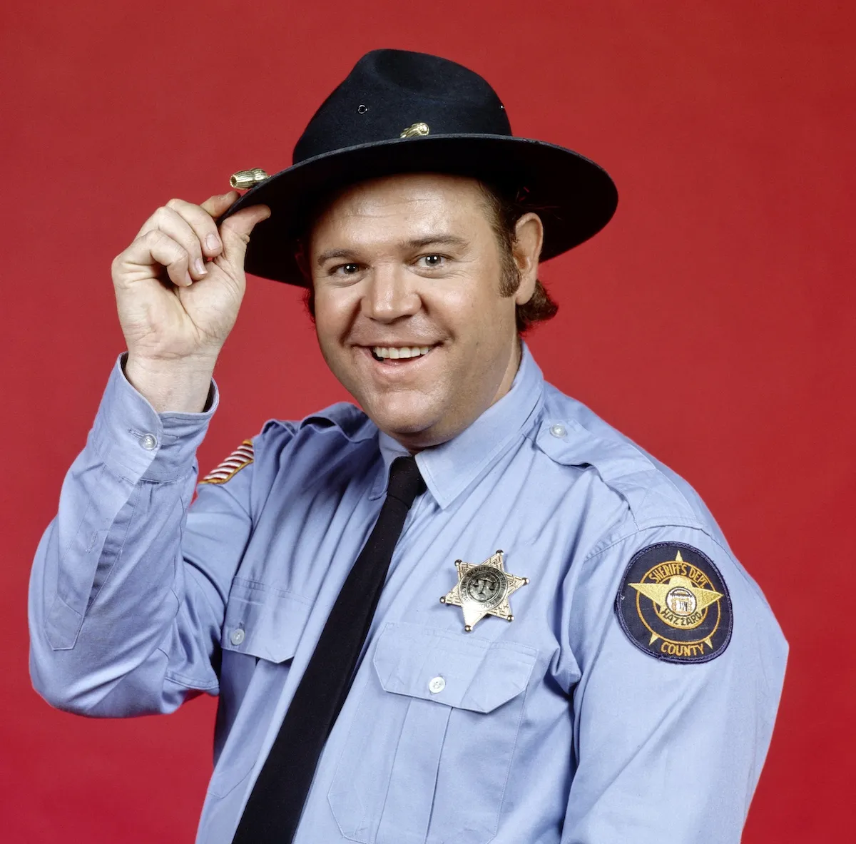 Portrait of Rick Hurst, wearing a cop uniform, as Cletus Hogg in 'The Dukes of Hazzard'