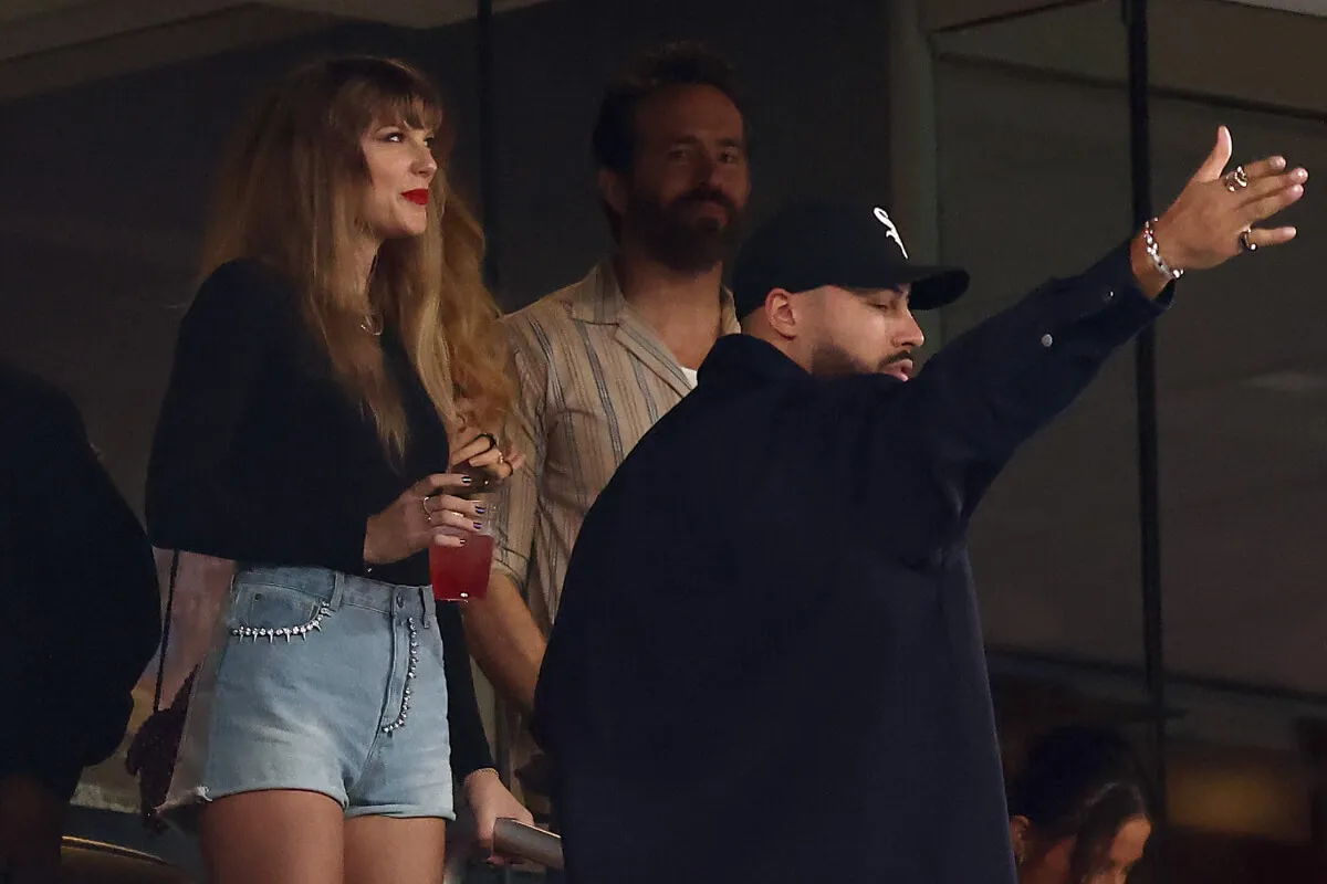 Taylor Swift and Ryan Reynolds stand in a box at the Kansas City Chiefs Game.