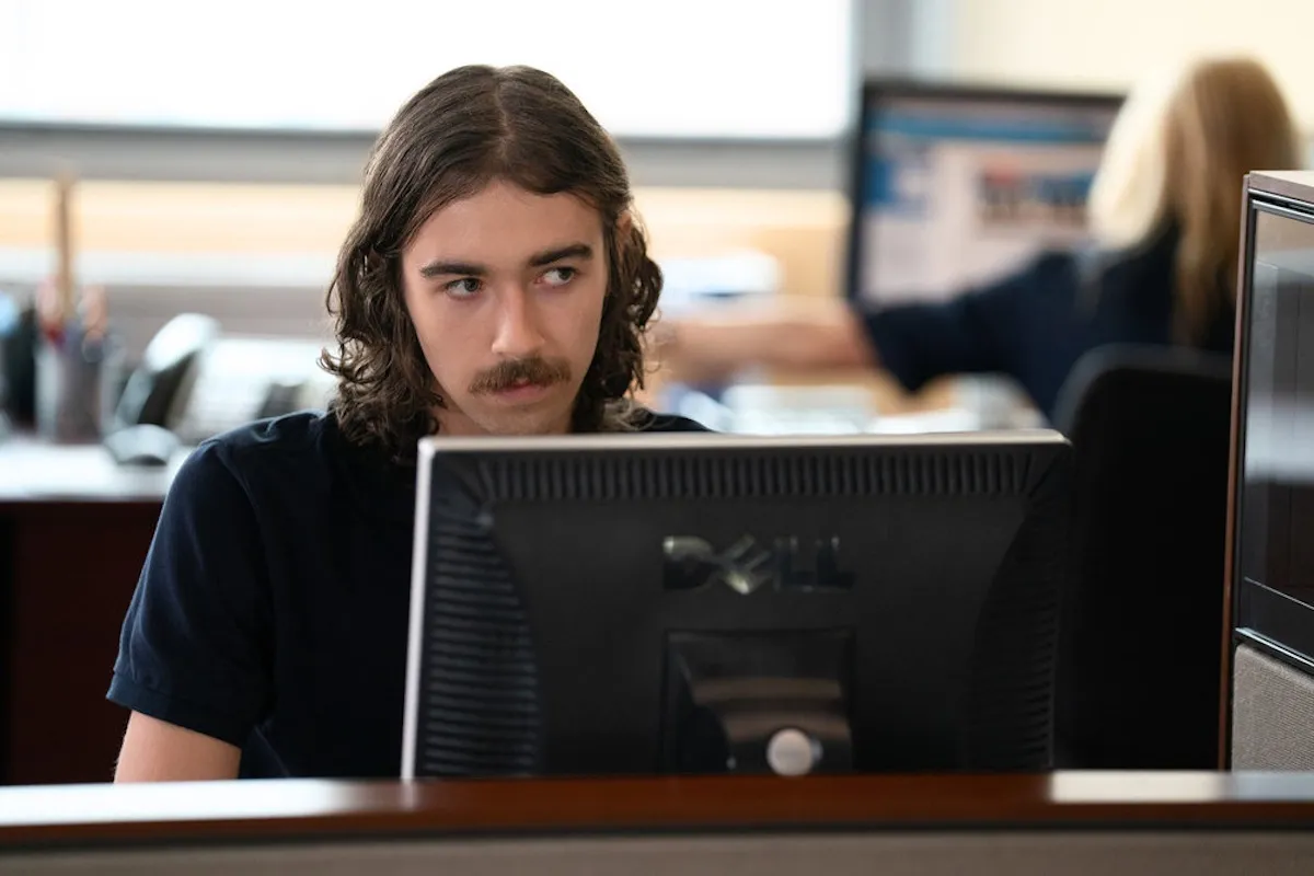 Finnigan McCormack sitting in front of a computer monitor in 'The hunting Party'