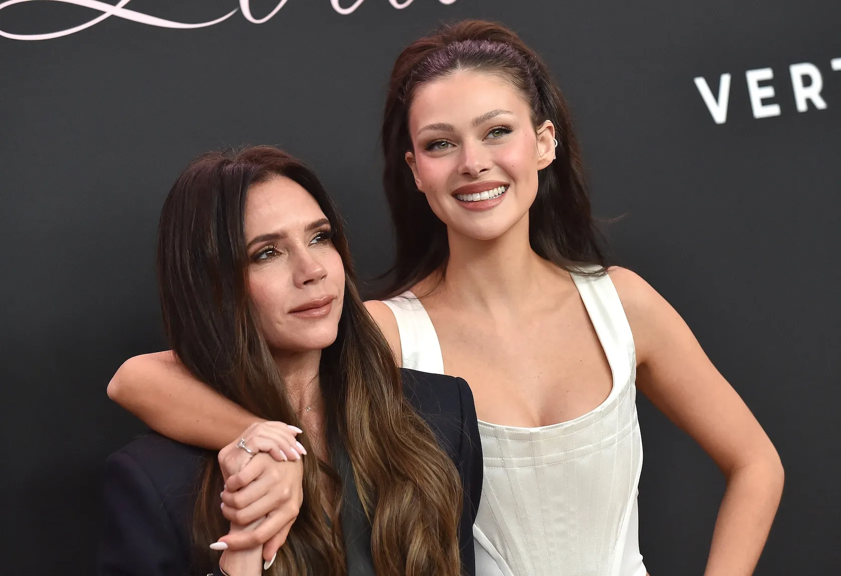 Nicola Peltz smiling with her arm around Victoria Beckham in 2024