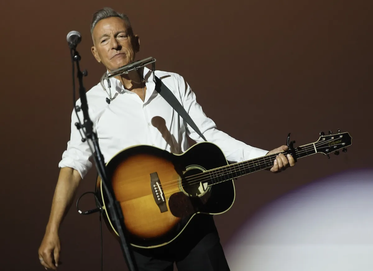 Bruce Springsteen in a white shirt and playing a guitar