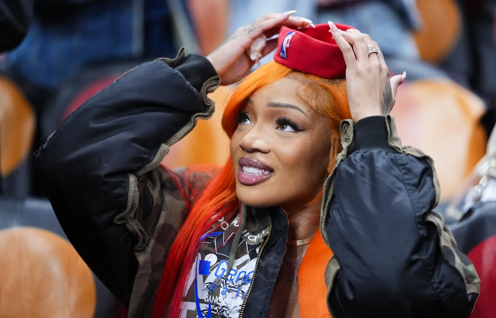 Rapper GloRilla wearing the headband of Brandon Ingram of the Toronto Raptors. She's looking up and smiling while holding the headband.