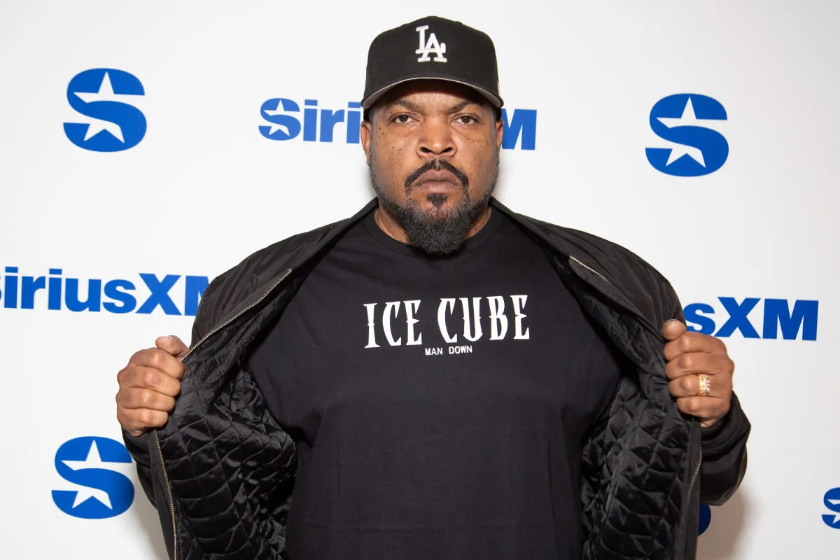 Ice Cube wears an LA hat and holds open his jacket to reveal a shirt that reads "Ice Cube."