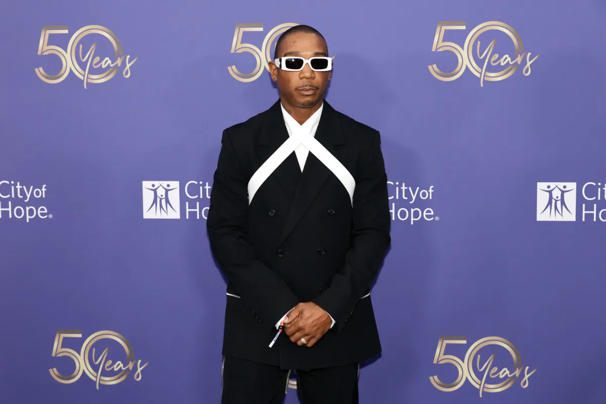 Ja Rule wears white sunglasses and a suit. He stands with his hands clasped.