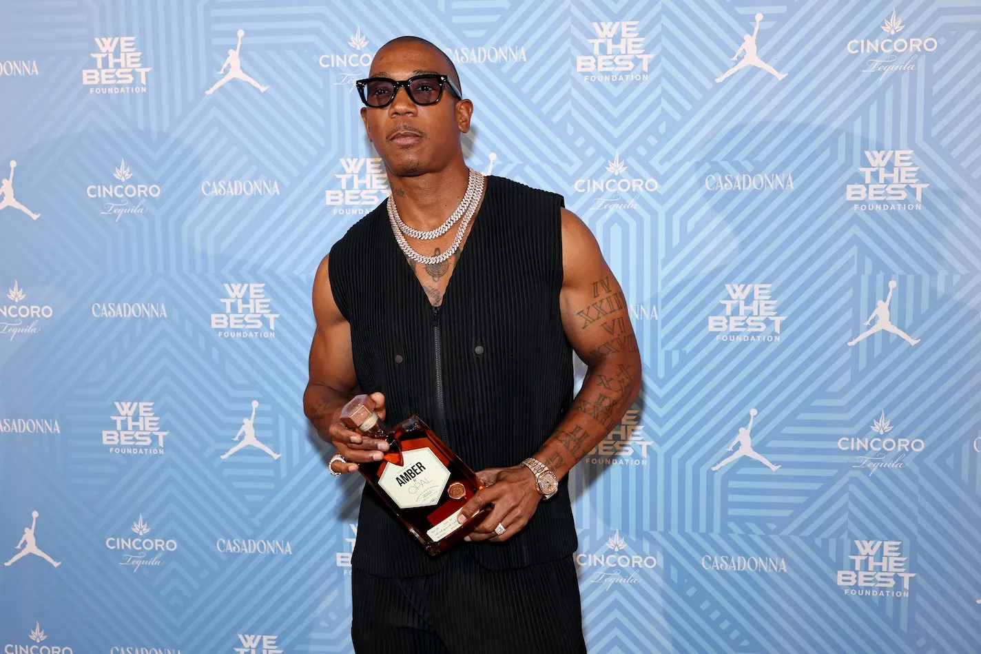 Ja Rule in a black sleeveless top holding a bottle of alcohol