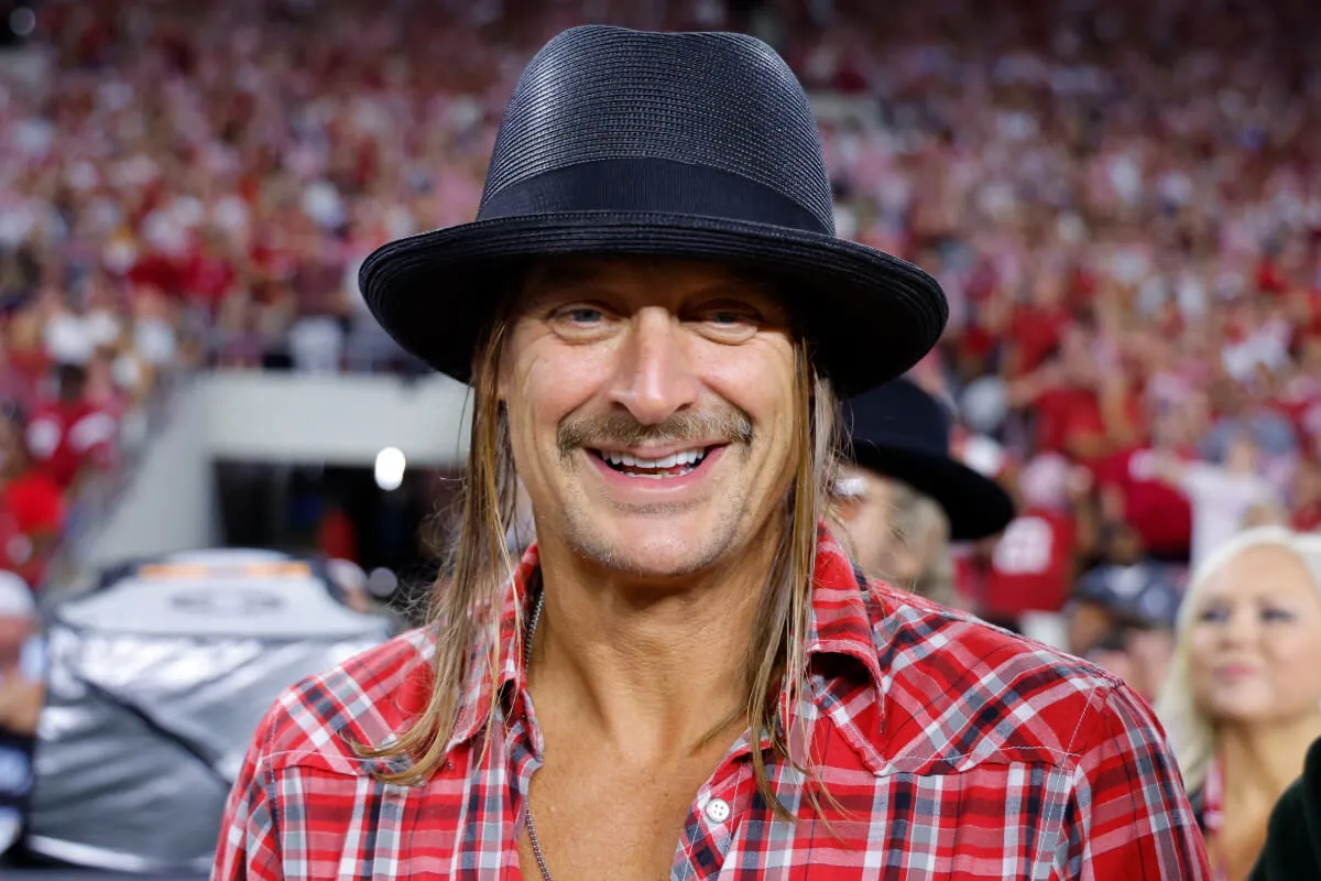 Kid Rock wears a black fedora and red plaid shirt.