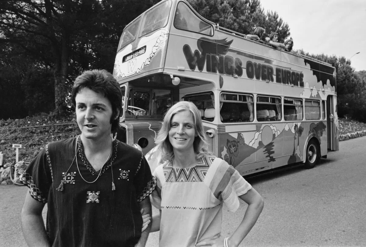 A black and white picture of Paul and Linda McCartney in front of a Wings tour bus.