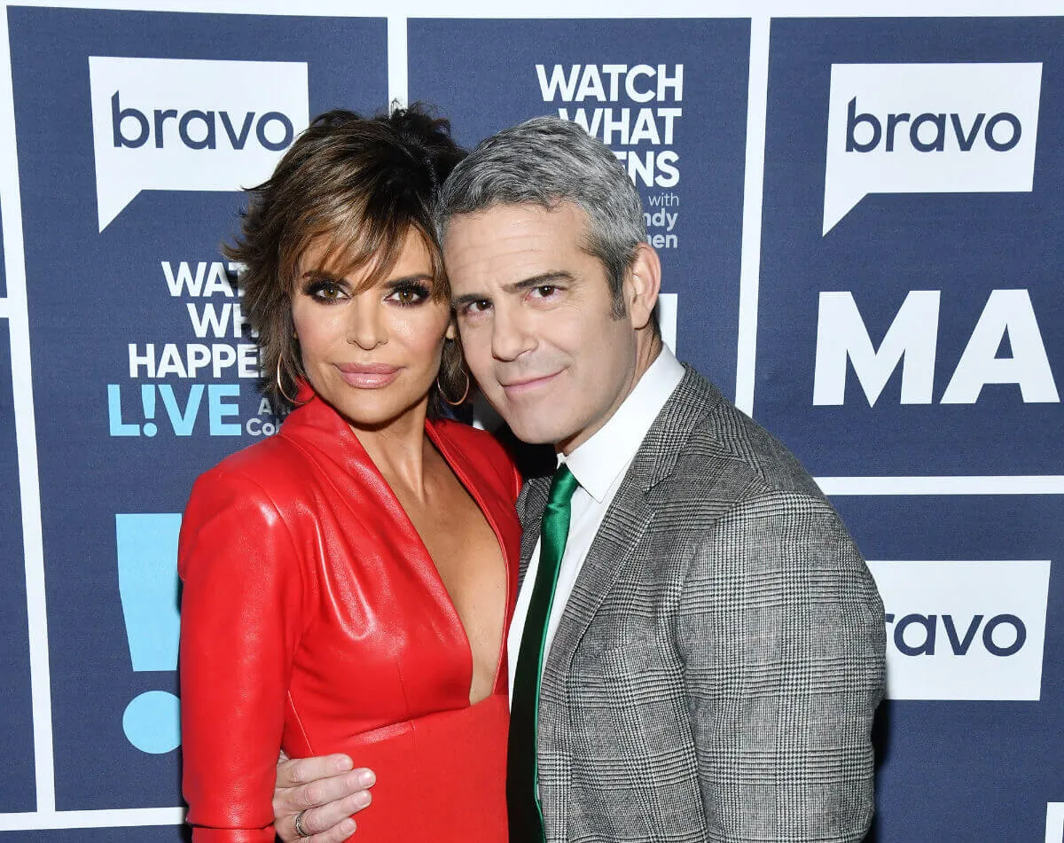 Lisa Rinna wears red and embraces Andy Cohen. He wears a gray suit.