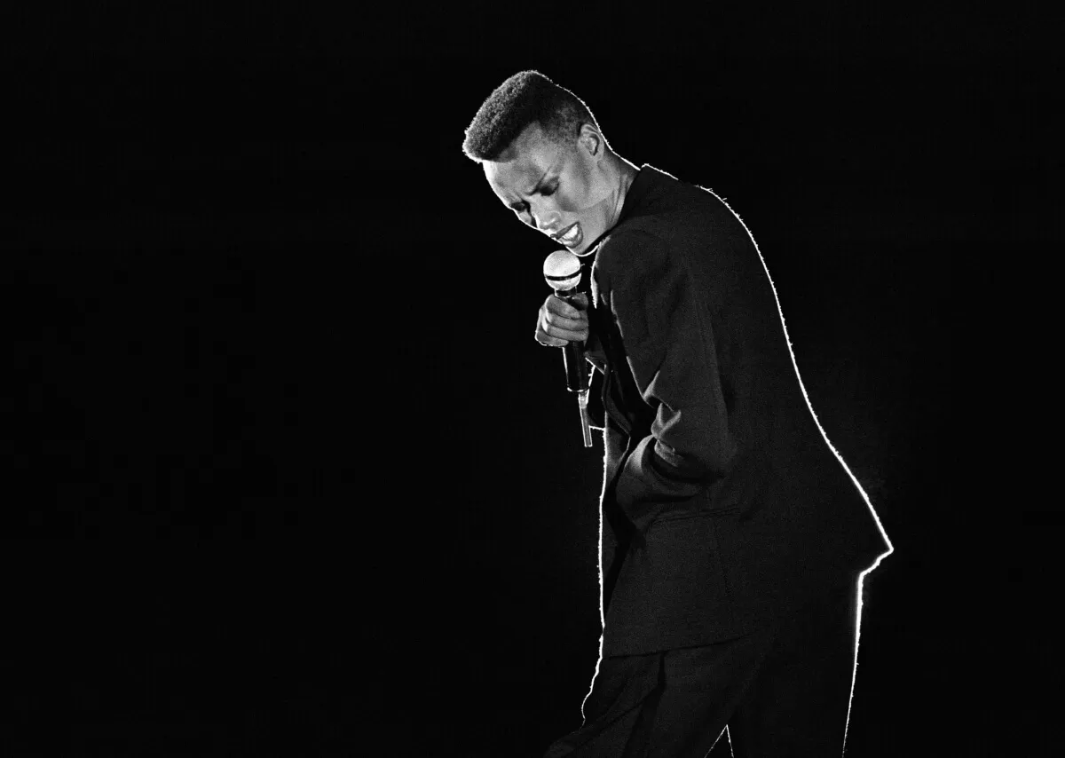 A black and white picture of Grace Jones, who did not want her music in the 'Melania' documentary, singing into a microphone.