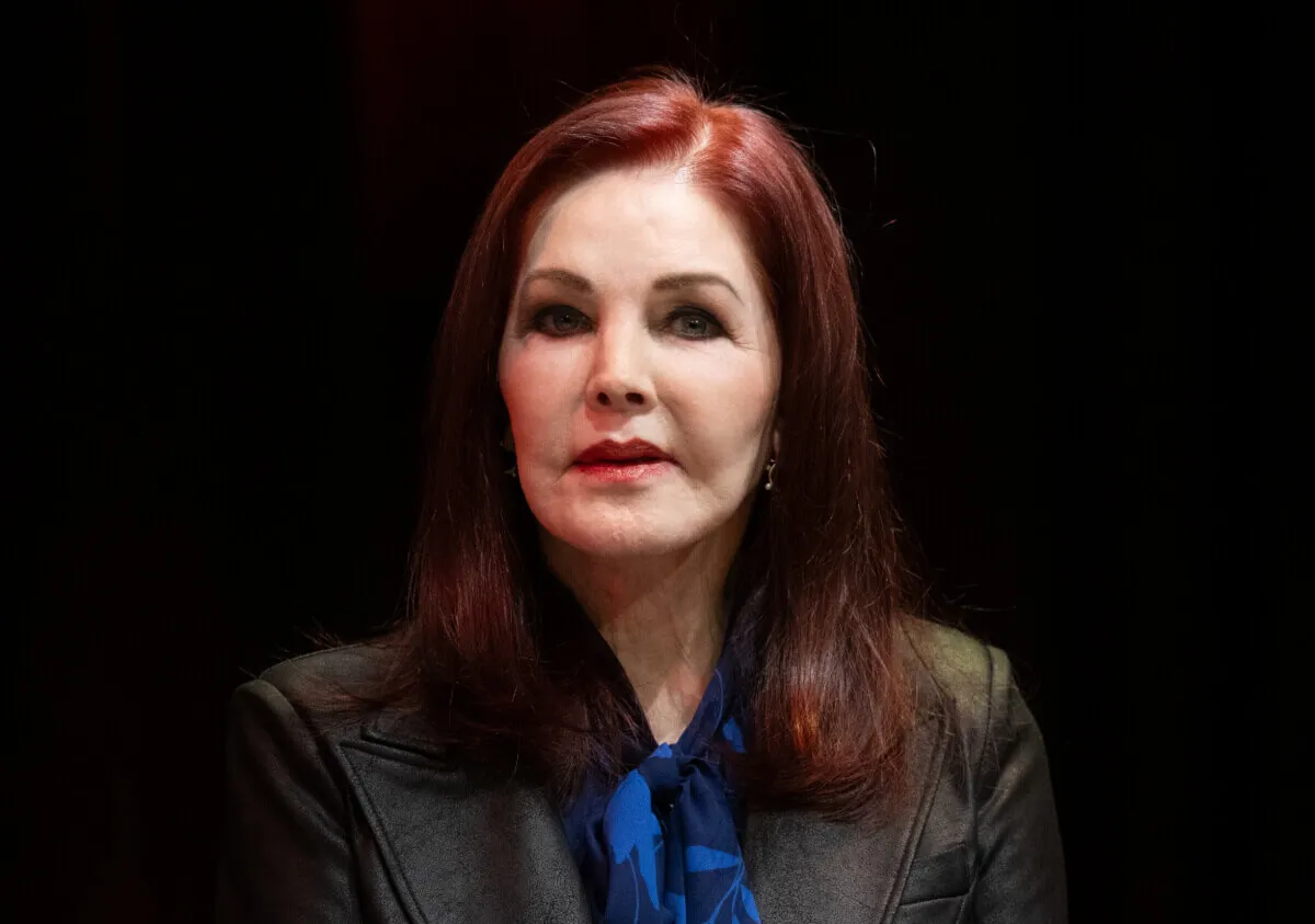 Priscilla Presley wears a black shirt with a blue neck tie.