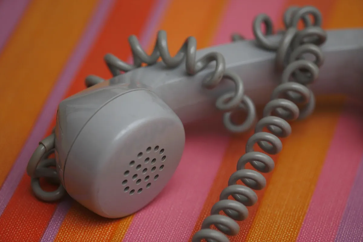 A gray telephone handset on a striped background