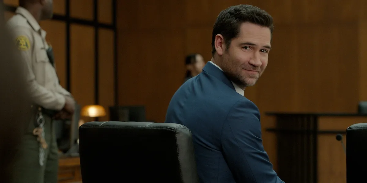 Manuel Garcia-Rulfo as Mickey Haller, looking over his shoulder while seated in court, in 'The Lincoln Lawyer' Season 4