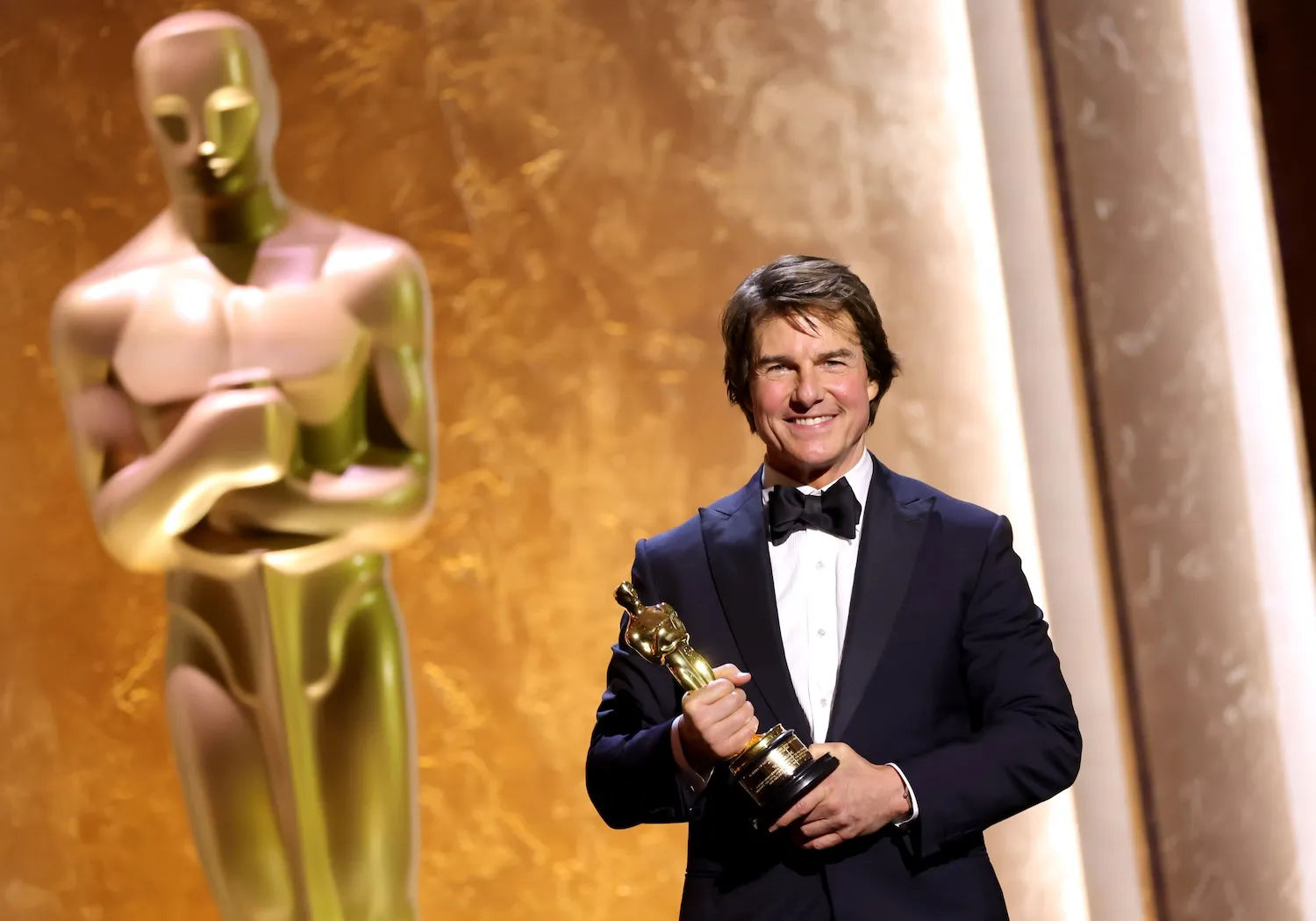 Tom Cruise smiling in a tuxedo and holding a statue at the 16th Governors Awards