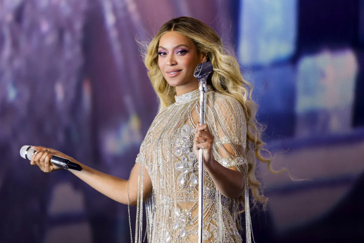 Beyonce wears a white bodysuit and holds a microphone.