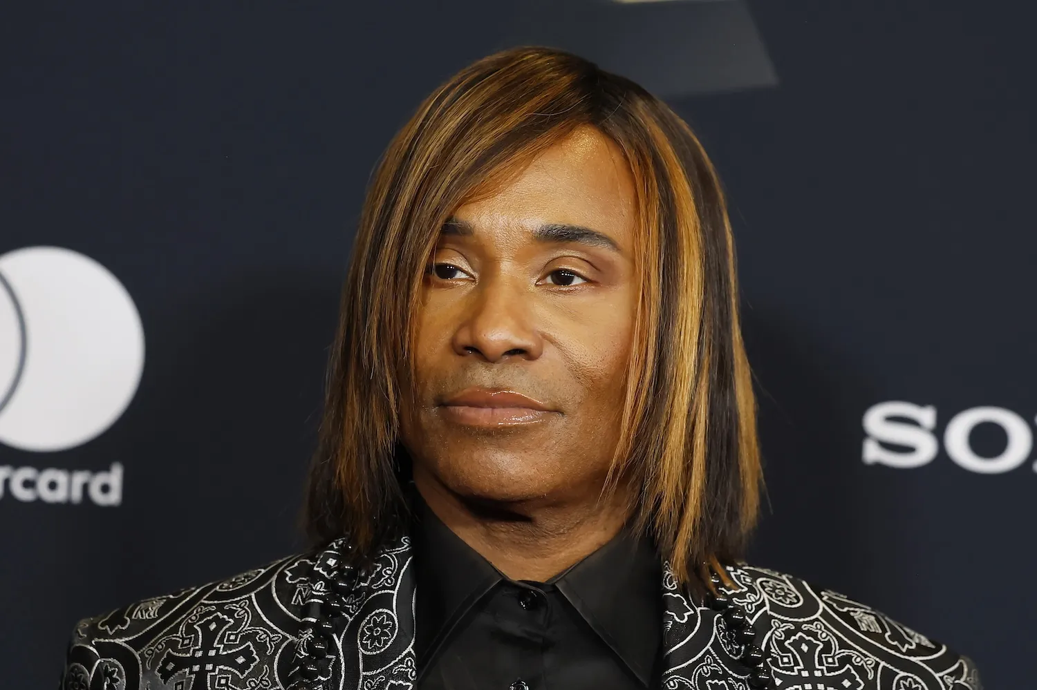 A close-up of Billy Porter at the 68th GRAMMY Awards pre-GRAMMY gala. His hair is chin-length, and he's wearing a gray patterned blazer
