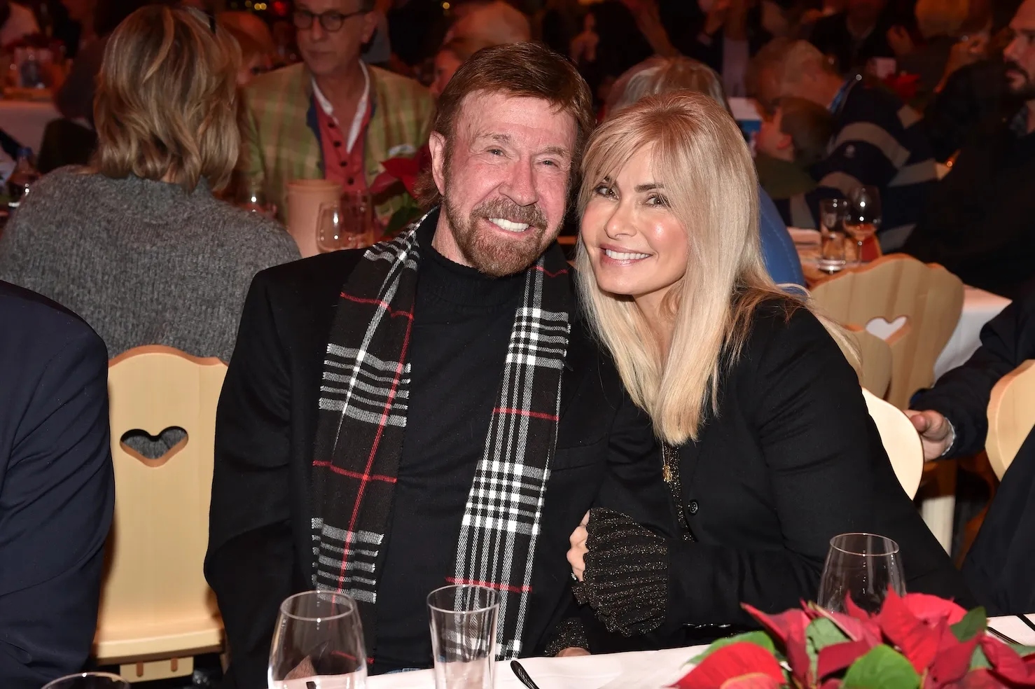 Chuck Norris and wife Gena O'Kelley sitting next to each other, leaning in, and smiling
