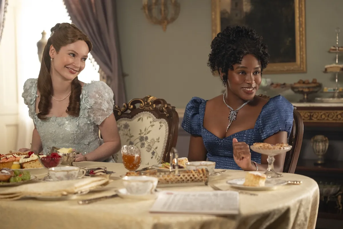 Francesca and Michaela sititng next to each other at a table in 'Bridgerton' Season 4