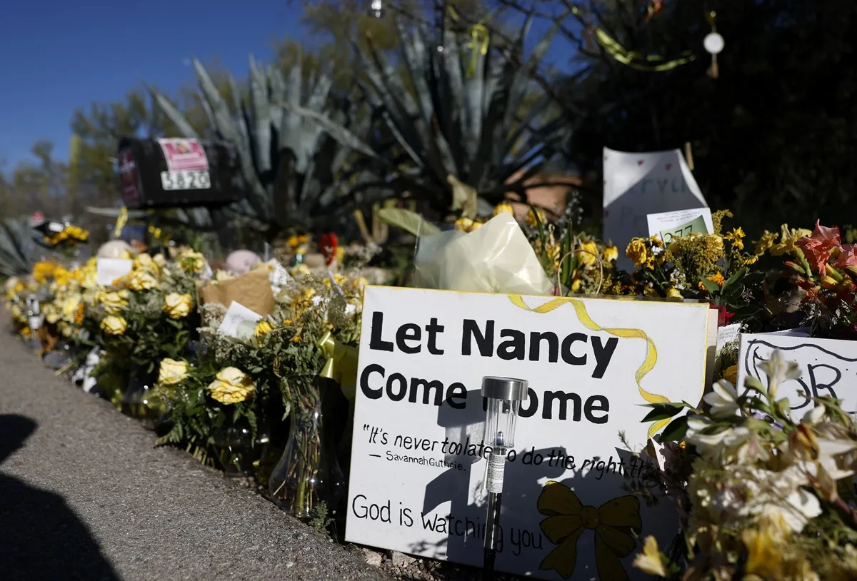 Flowers and signs are seen in a makeshift memorial in front of the home of Nancy Guthrie on February 27, 2026 in Tucson, Arizona. Law enforcement officials continue to search for Nancy Guthrie, the 84-year-old mother of U.S. journalist and television host Savannah Guthrie, after she was abducted from her home on the morning of February 1st.
