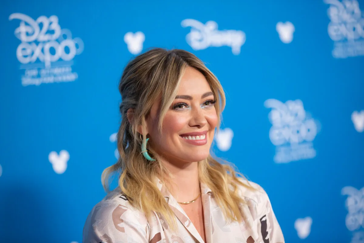Hilary Duff wears a white shirt and blue hoop earrings.
