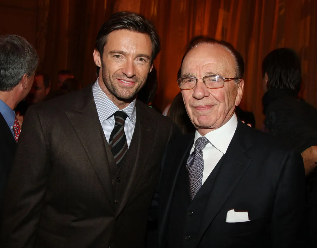 Hugh Jackman stands with Rupert Murdoch. They both wear suits.