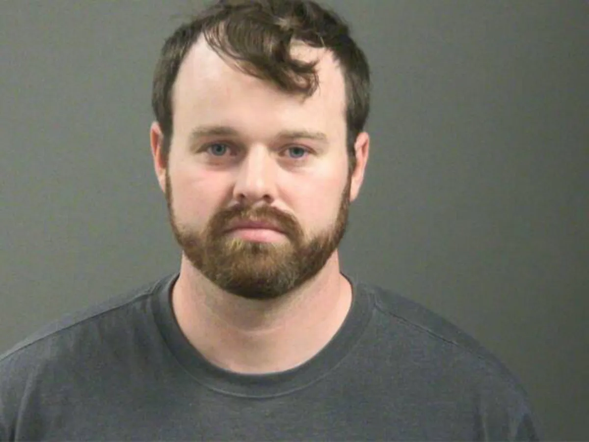 Joseph Duggar, with a beard and mustache, in his mugshot