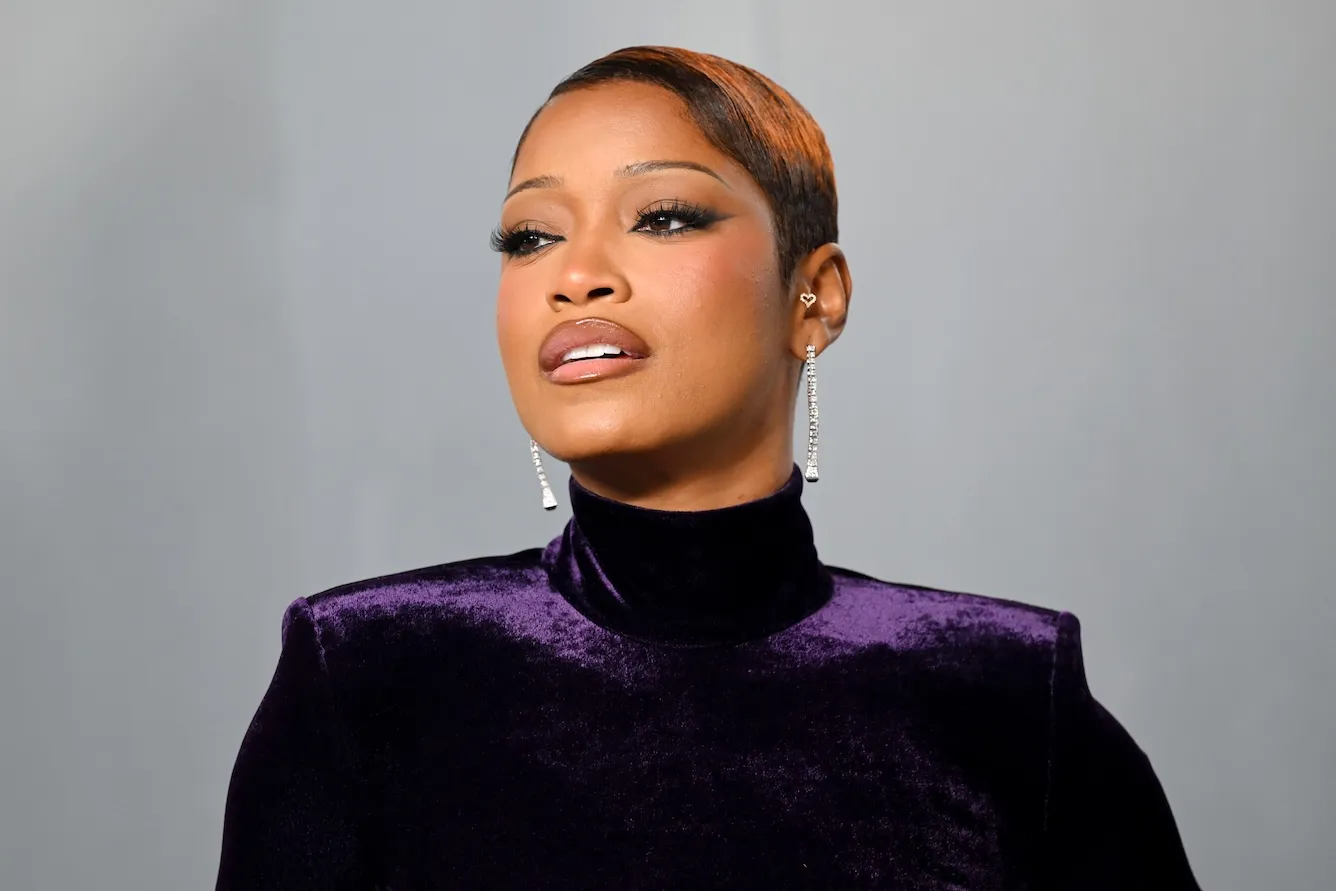 A close-up of Keke Palmer with her hair slicked back as she's wearing a high-neck purple dress
